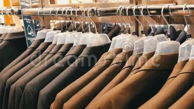 棕色和灰色的男士`夹克挂在商场的<strong>男士服装</strong>店的衣架上。 一大群男人穿`西装